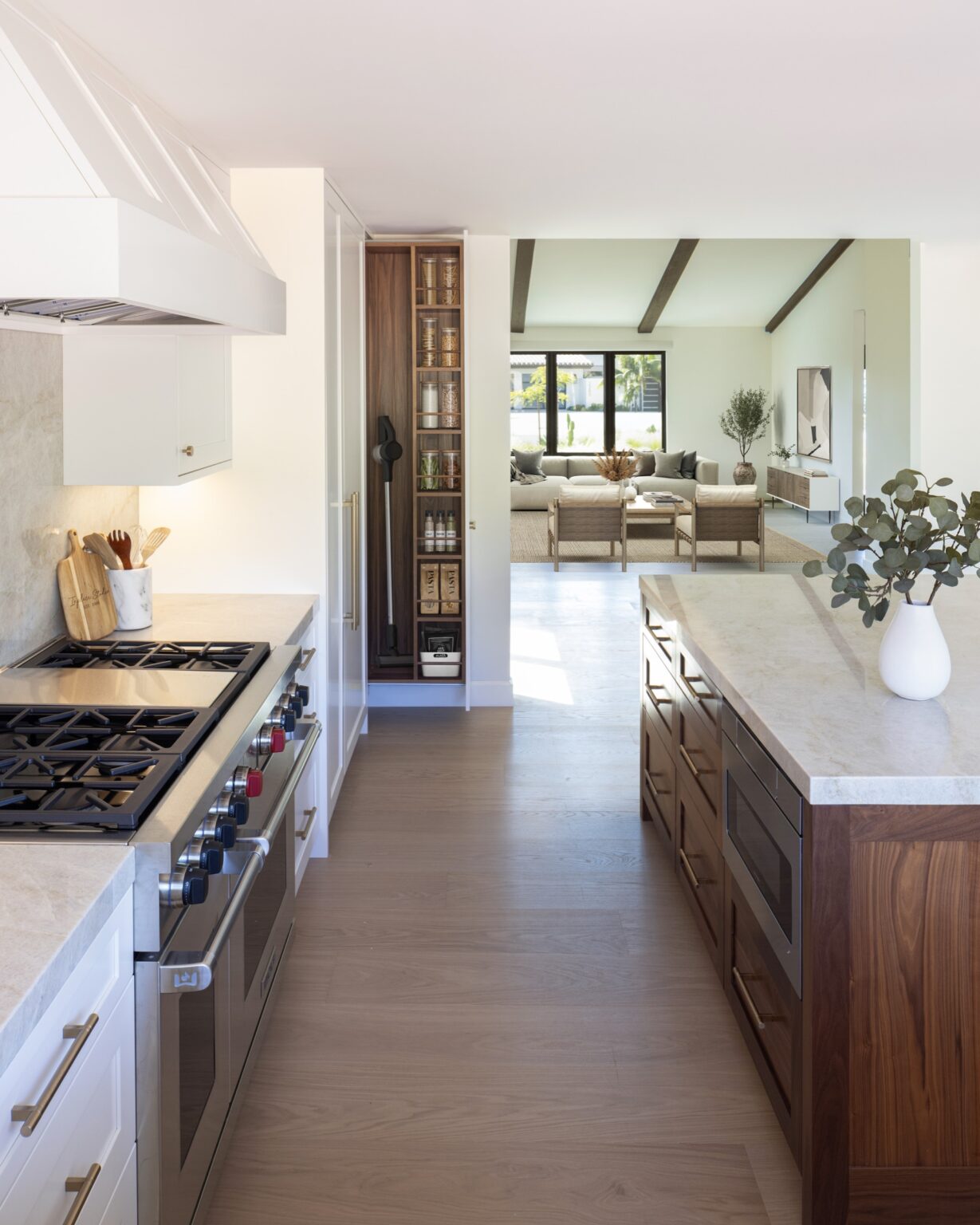 White Wood-Mode Chatham cabinetry with a Wolf range, walnut open pantry tower and walnut island opening to the living room