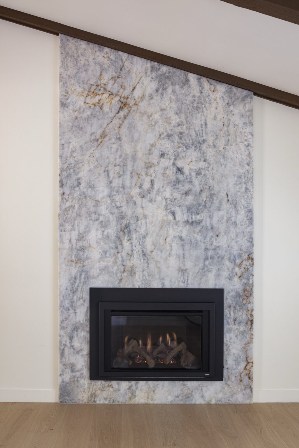 Floor-to-ceiling natural stone fireplace surround under a beamed ceiling in a La Jolla living room remodel by Inplace Studio