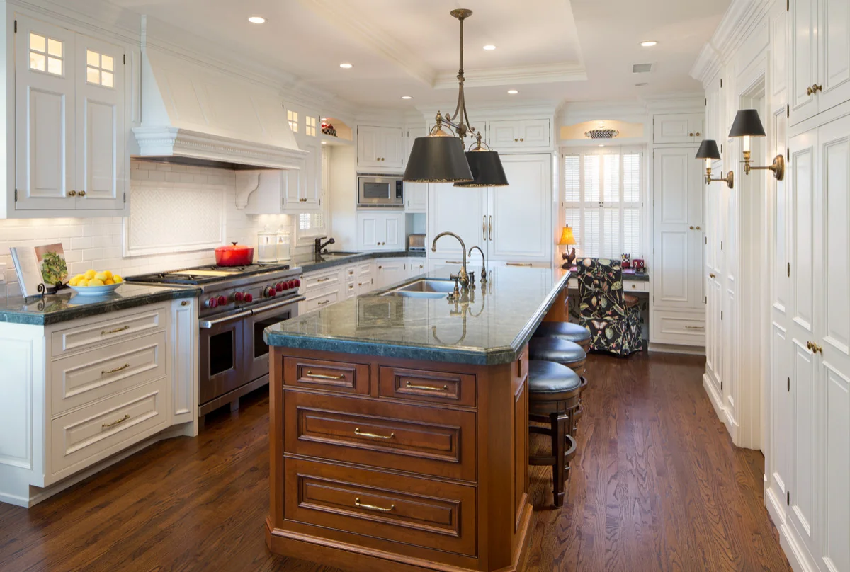 Modern kitchen with elegant custom white cabinets and wood island, featuring a marble countertop, modern appliances