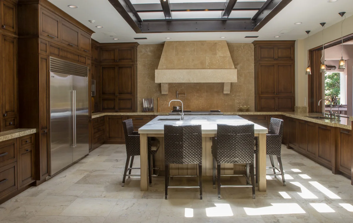 Spacious kitchen with custom wooden cabinetry, marble island, and elegant lighting, perfect for a modern transformation.