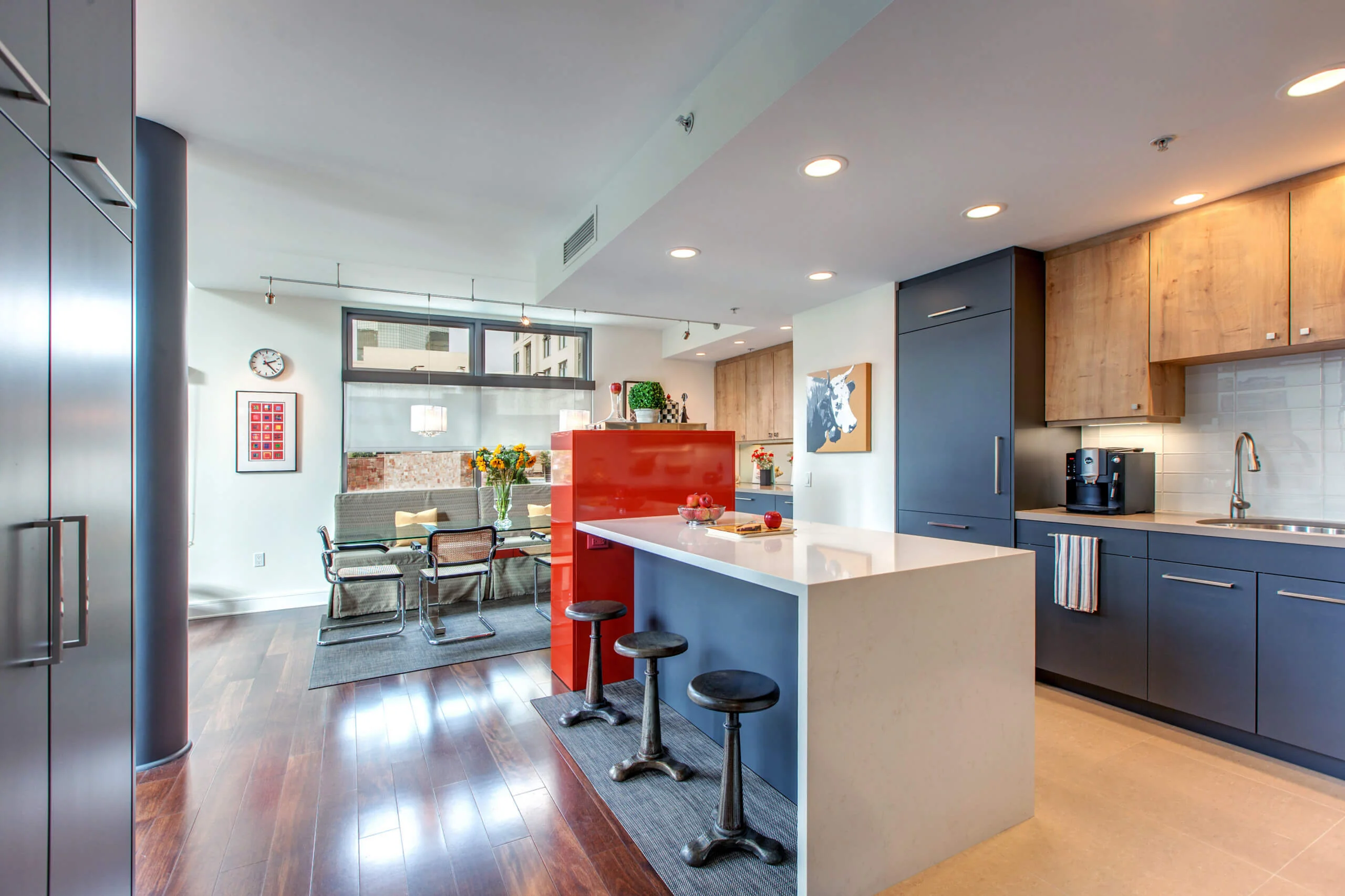 Modern kitchen and dining area with custom cabinetry and sleek design, featuring dark wood floors, contemporary lighting